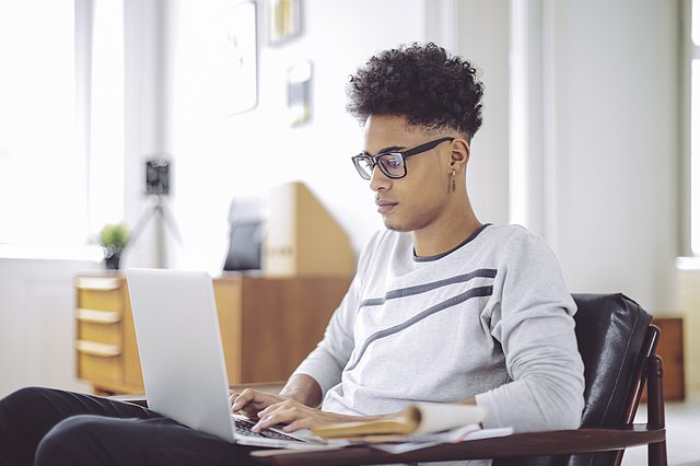 Ein junger Mann sitzt am Laptop.